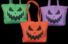 Load image into Gallery viewer, Three quilted Halloween tote bags with black jack-o'-lantern faces, shown in green, orange, and purple.
