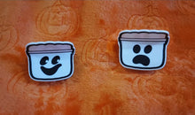 Load image into Gallery viewer, A set of two hair clips with designs resembling spooky buckets, with varying facial expressions, placed on an orange background with a Halloween theme.
