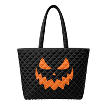 Load image into Gallery viewer, A black quilted tote bag with an ornage jack-o'-lantern face design on the front.
